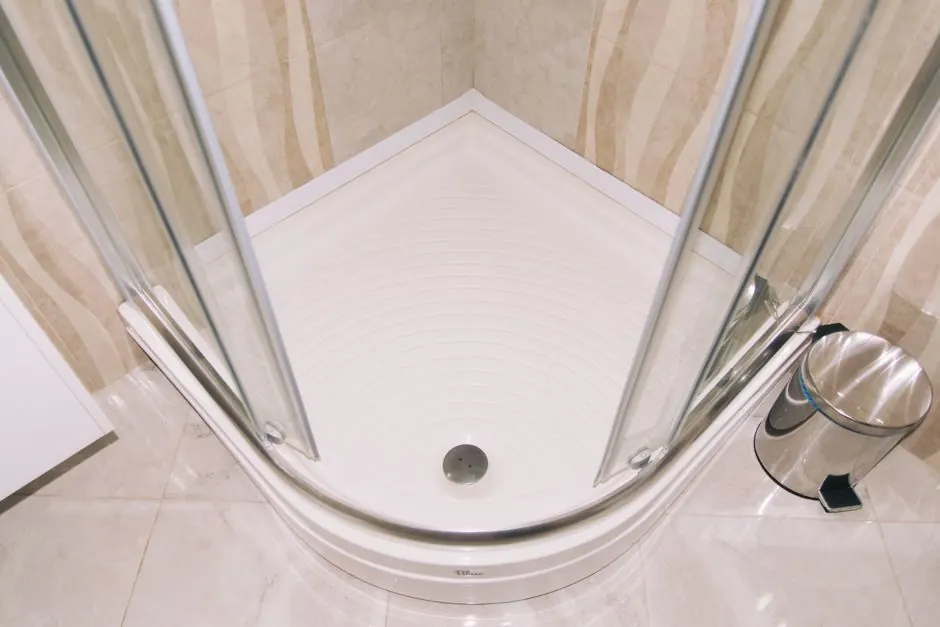 A clean, modern corner shower enclosure with glass doors in a tiled bathroom setting.