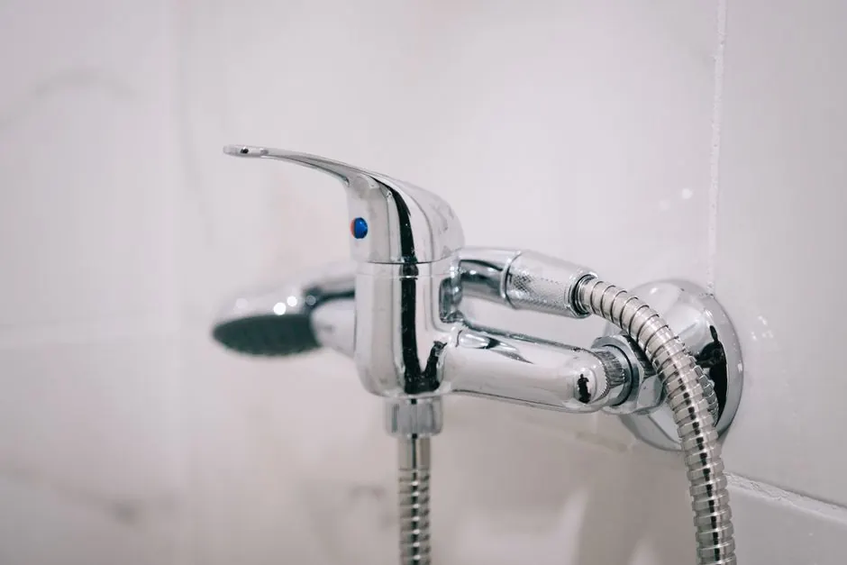 A detailed view of a sleek chrome shower faucet in a clean bathroom setting.